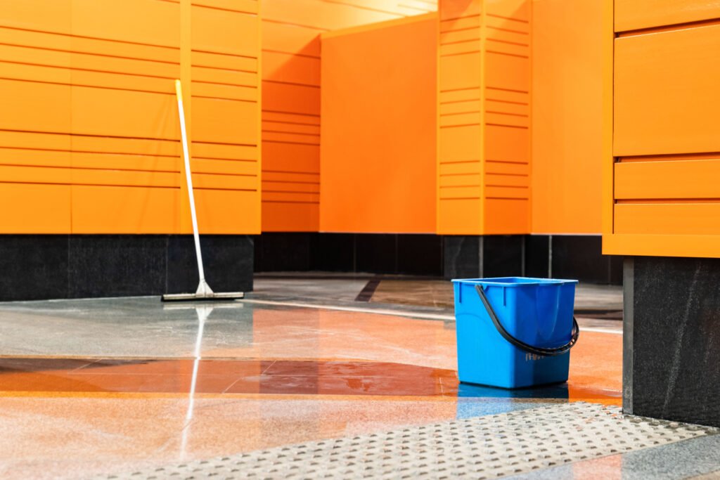 Disinfection of subway stations during the coronavirus pandemic. Blue plastic bucket and mop against the background of an empty station with orange walls.
