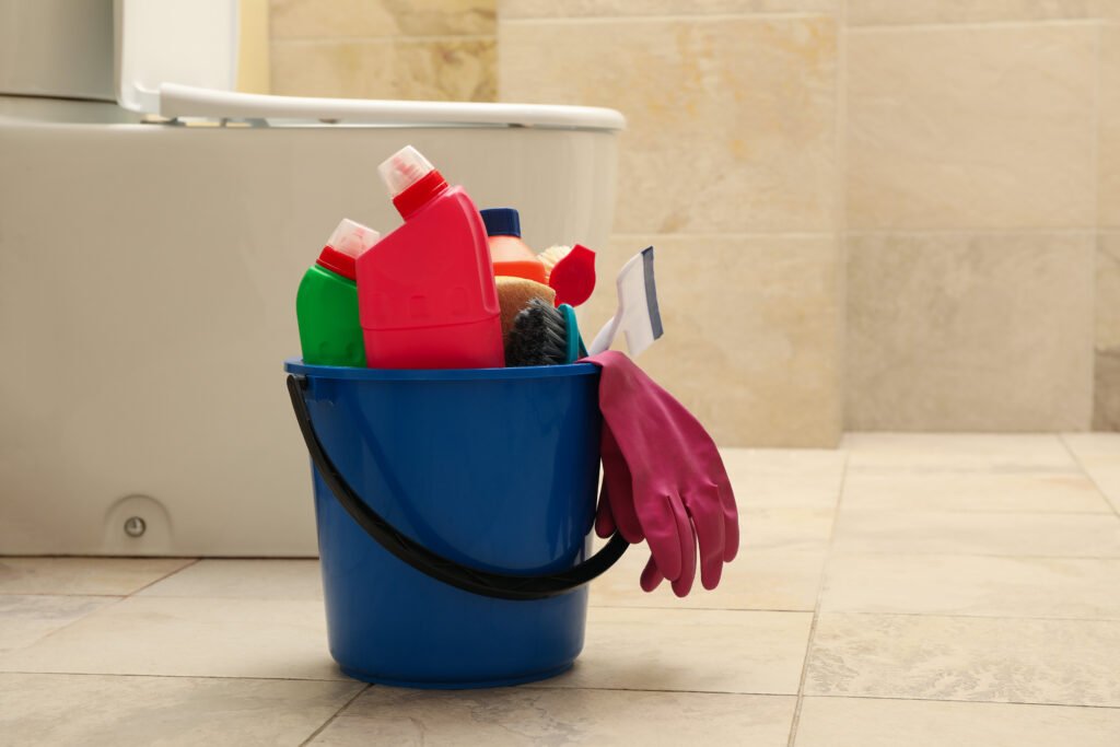 Bucket with cleaning products in modern bathroom
