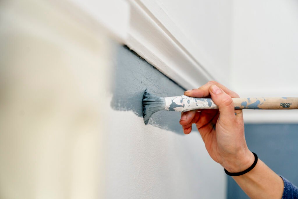 Close up of hand using paintbrush to paint wall
