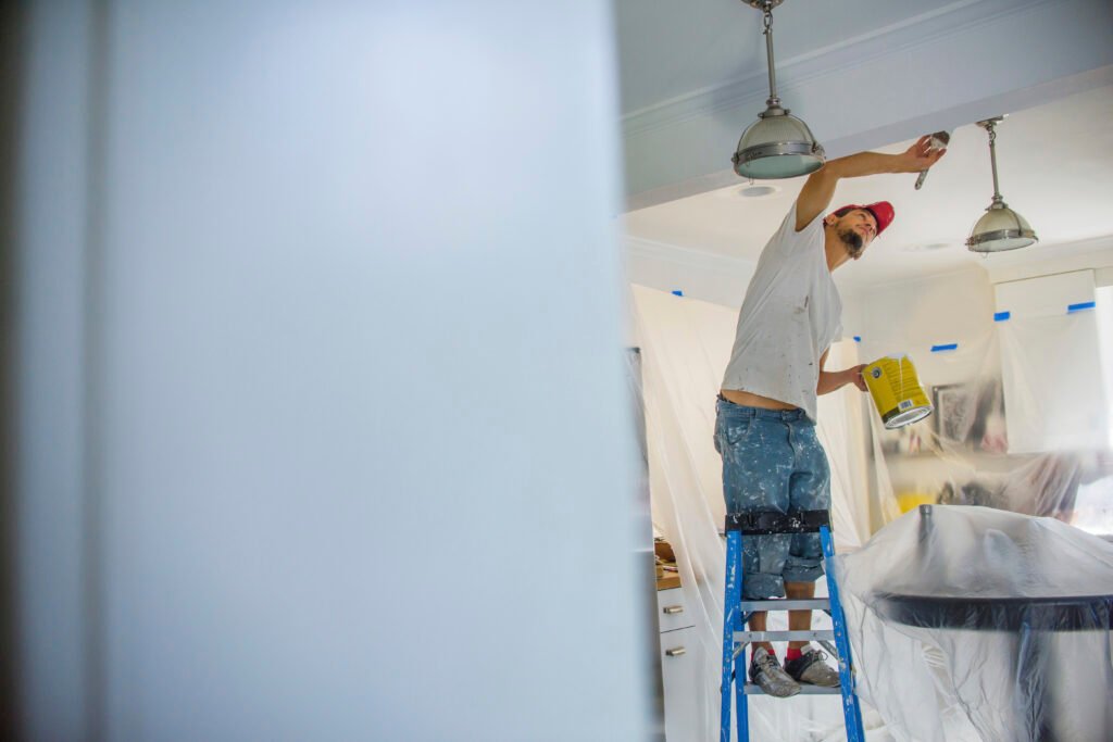 Man up stepladder painting ceiling
