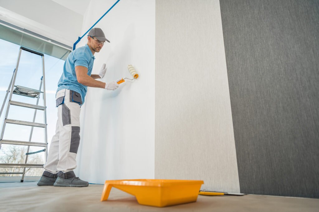 Caucasian Men in His 40s Applying Modern Canvas Textured Vinyl Wallpaper in the Apartment Room. Interior Renovation Theme.