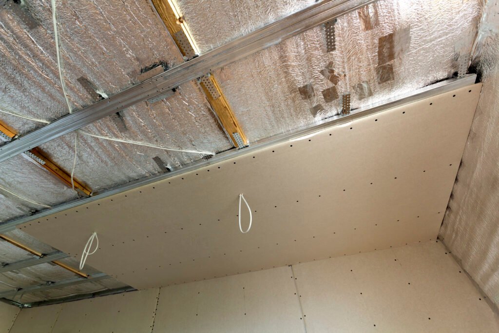 Angle bottom view of unfinished room under construction and renovation with silver aluminum insulation foil and drywall on walls and ceiling. Professional work, reconstruction and renovation concept.